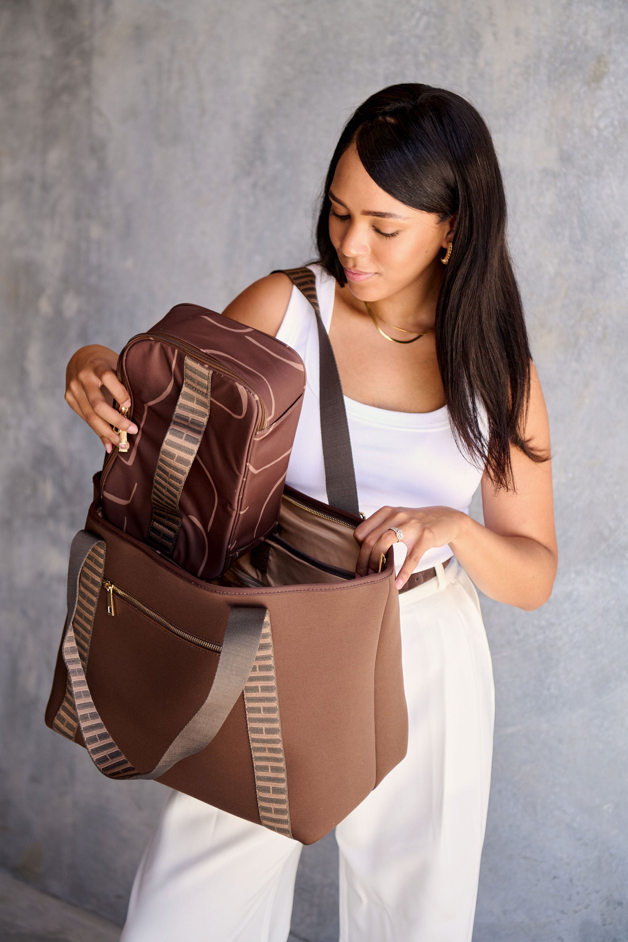 Woman opening a chocolate brown tote bag with a make up case