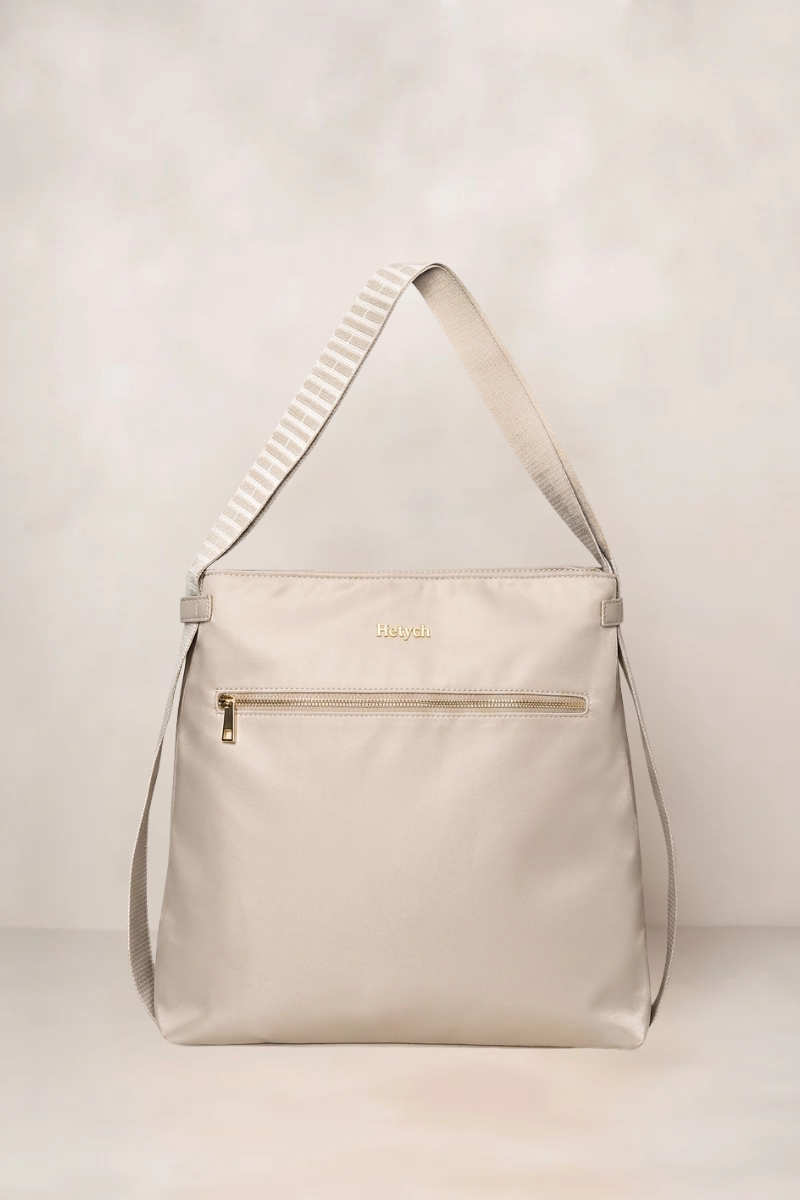 Taupe convertible tote backpack handbag with a gold zipper on a light gray background