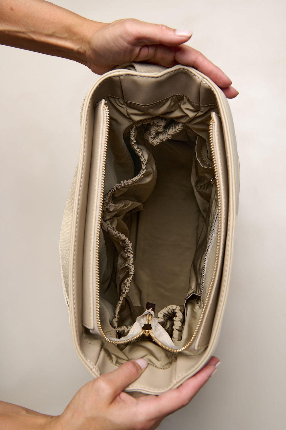 Taupe Beige backpack tote bag held open by hands against a beige background
