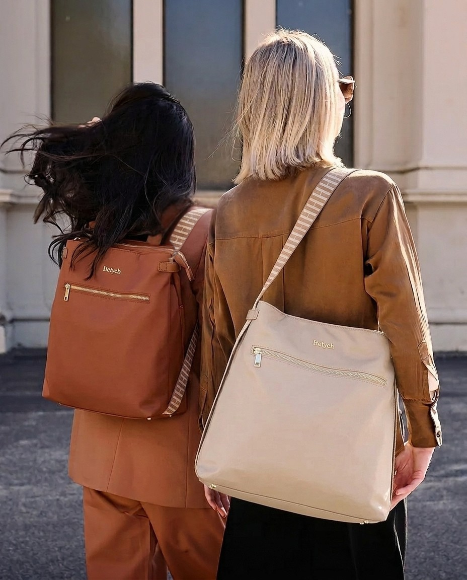 Two people walking outdoors, one with a brown backpack and the other with a beige handbag, both carrying Heiych bags.